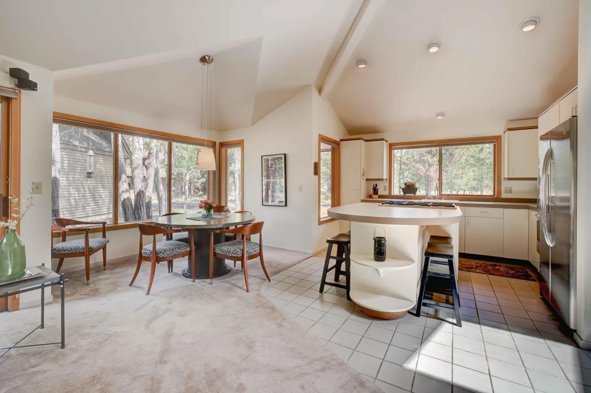 A cozy dining area and kitchen filled with morning light, large windows opening to natural views, and a spacious table ideal for family meals and casual gatherings after a day of Sunriver activities.
